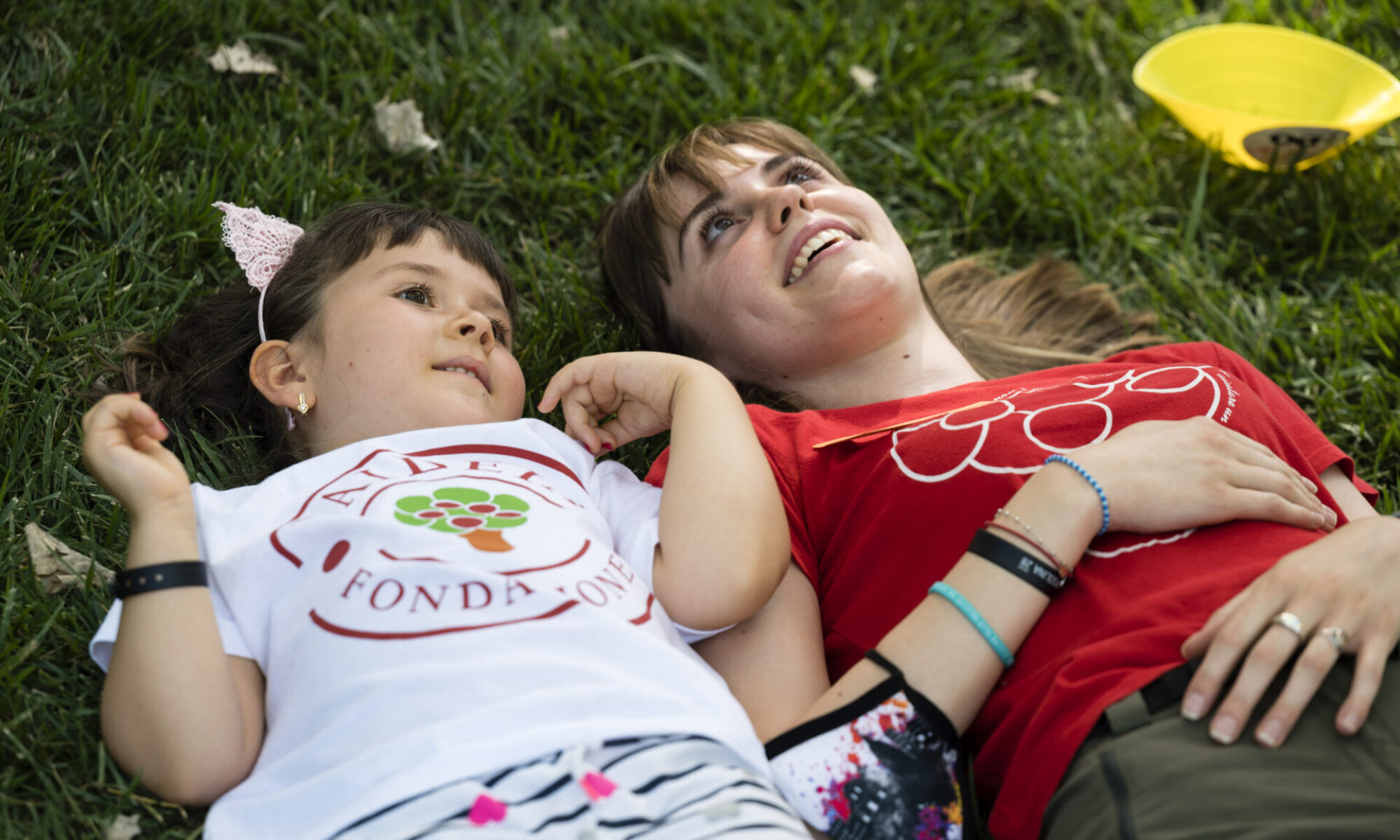 Bambina guarda il cielo vicino a una Volontaria Paideia